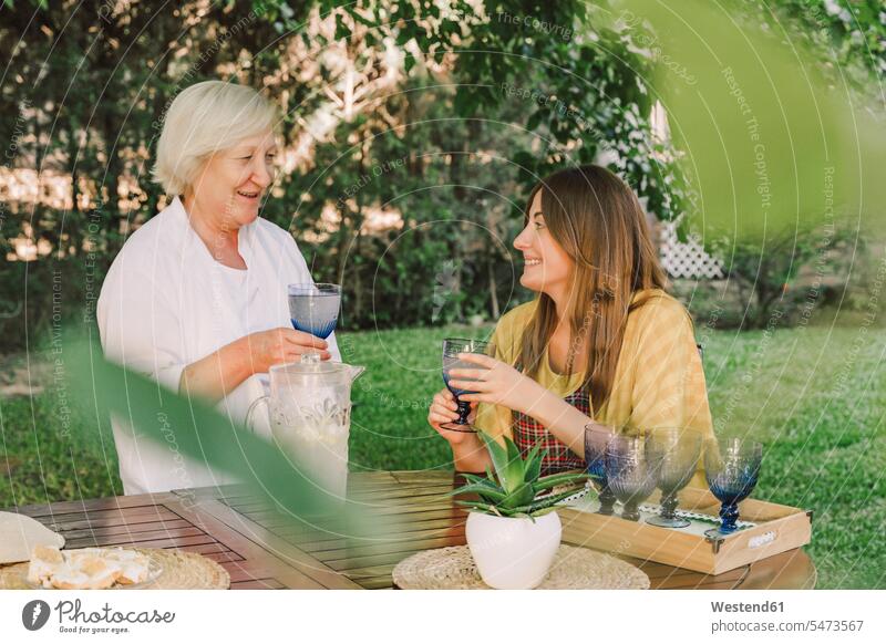 Lächelnde Mutter und Tochter genießen Getränke während sie sich im Hof unterhalten Farbaufnahme Farbe Farbfoto Farbphoto Spanien Freizeitbeschäftigung Muße Zeit