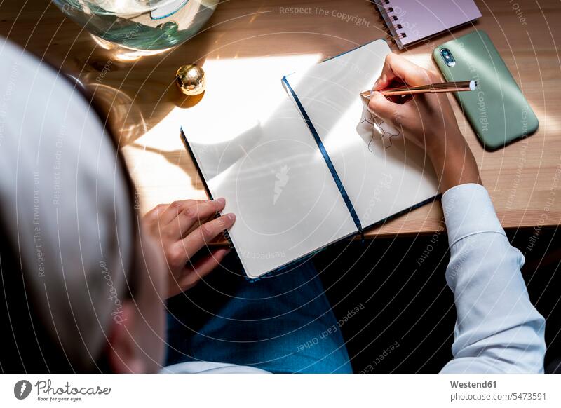 Mittlere erwachsene Frau, die zu Hause auf dem Schreibtisch Tagebuch zeichnet Farbaufnahme Farbe Farbfoto Farbphoto Spanien Innenaufnahme Innenaufnahmen innen