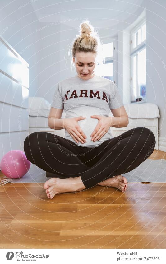 Schwangere Frau übt zu Hause mit einem Ball Bälle anfassen Berührung sitzend sitzt ausüben trainieren Übung entspannen relaxen entspanntheit relaxt zufrieden