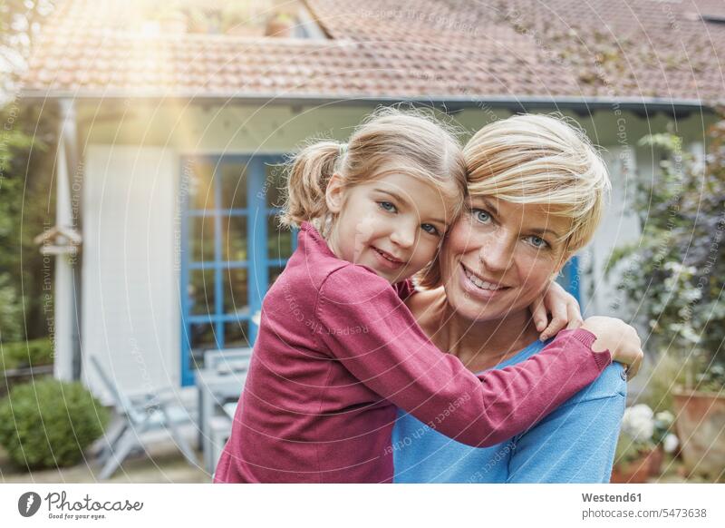 Porträt einer lächelnden Mutter mit Tochter vor ihrem Haus Häuser Haeuser glücklich Glück glücklich sein glücklichsein Portrait Porträts Portraits Mami Mutti