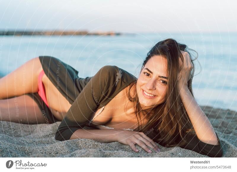 Schöne Frau entspannt am Strand bei Sonnenuntergang, Porträt Beach Straende Strände Beaches Sonnenuntergänge lächeln Entspannung Entspannen relaxen entspannen