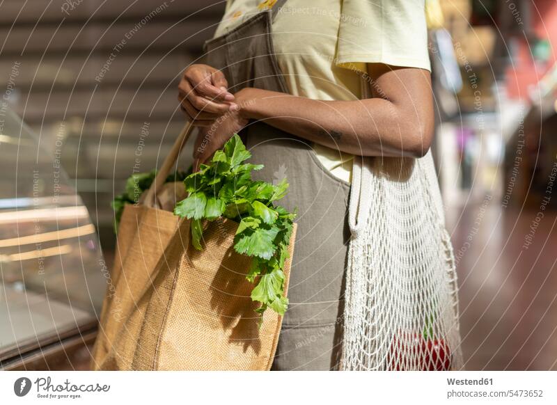 Mittelteil einer Frau, die in einer Markthalle Lebensmittel einkauft Leute Menschen People Person Personen Kunden Kundschaft Taschen Einkaufstaschen Kauf