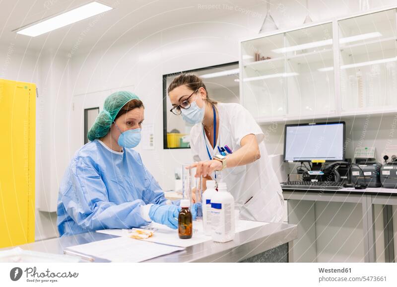 Apothekerinnen diskutieren während der Herstellung von Arzneimitteln im Krankenhaus im Labor Farbaufnahme Farbe Farbfoto Farbphoto Spanien Innenaufnahme