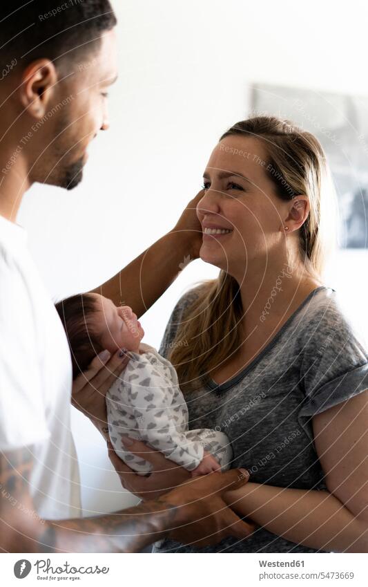 Glückliche Eltern halten neugeborenes Baby zu Hause Vater Papas Väter Vati Vatis Papis glücklich glücklich sein glücklichsein Augen geschlossen