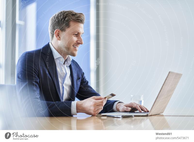 Geschäftsmann mit Kreditkarte und Laptop am Schreibtisch im Büro Job Berufe Berufstätigkeit Beschäftigung Jobs geschäftlich Geschäftsleben Geschäftswelt