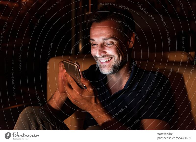 Porträt eines glücklichen reifen Mannes, der zu Hause ein Mobiltelefon benutzt Glück glücklich sein glücklichsein Männer männlich Zuhause daheim benutzen