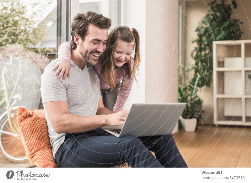 Junger Mann und kleines Mädchen surfen zusammen im Netz Deutschland auf dem Boden sitzen auf dem Boden sitzend Laptop benutzen Laptop benützen ein Elternteil
