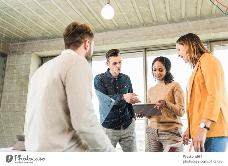 Junge Geschäftsleute, die sich im Büro treffen und sich ein Tablett teilen Arbeitskollege Arbeitskollegen Kollege Partner Partnerschaften Job Berufe