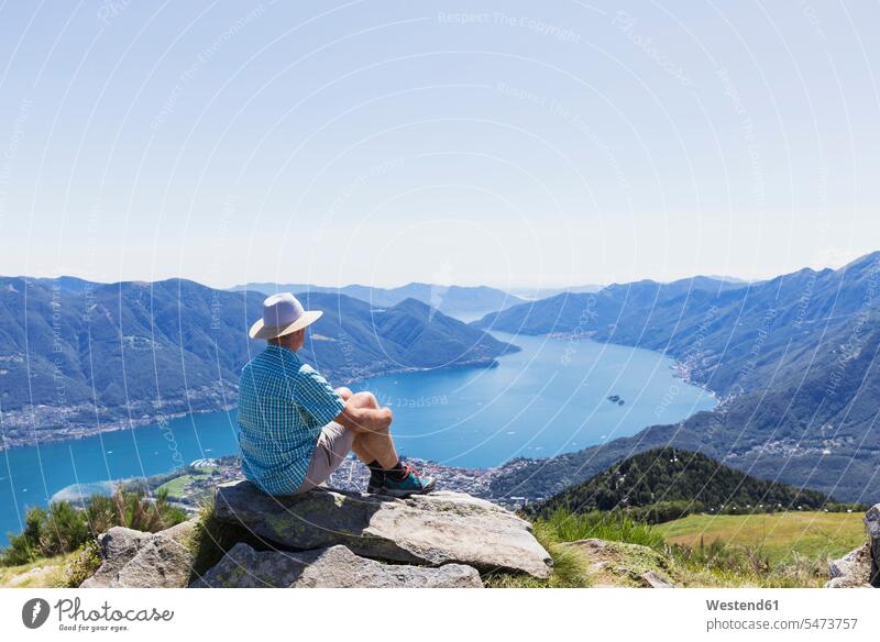 Wanderer auf dem Gipfel der Cimetta mit Blick auf den Lago Maggiore und Ascona, Locarno, Tessin, Schweiz Touristen Hemden sehen sehend sitzend sitzt Wanderung