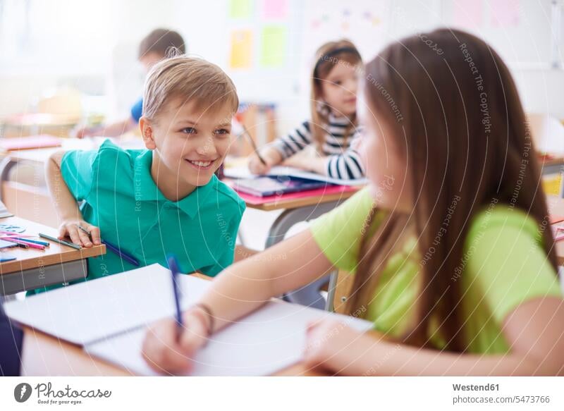 Schuljunge lächelt Schulmädchen in der Klasse an lächeln Schulklasse Schule Schüler Schülerin Schulkind Bildung Schulheft Aufgabe differenzierter Fokus