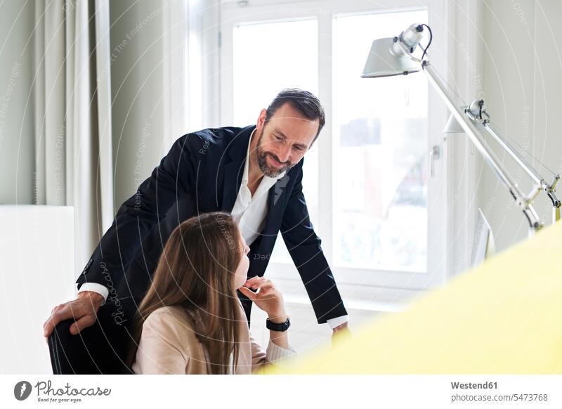 Geschäftsmann und Angestellter sprechen am Schreibtisch im Büro Team Beruf Chef Geschäftsfrau Manager Fenster Geschäftskleidung arbeiten flirten lächeln