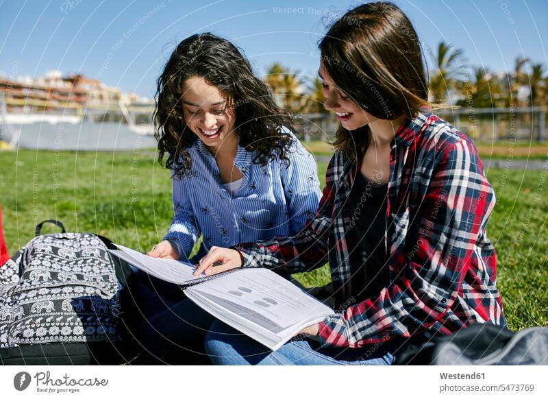 Zwei lächelnde Studentinnen sitzen im Park und lernen gemeinsam Parkanlagen Parks Gemeinsam Zusammen Miteinander Hochschülerin Hochschülerinnen