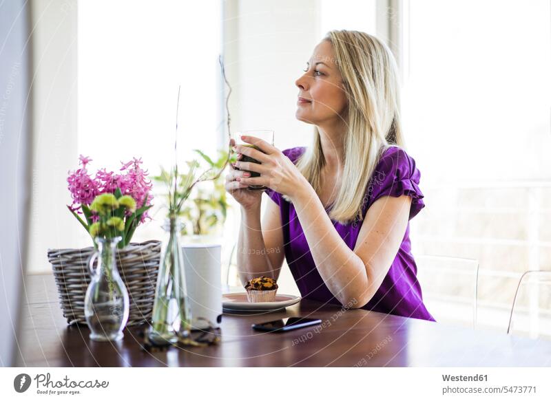 Reife Frau sitzt am Tisch und entspannt sich bei einem Glas Kaffee sitzen sitzend Tische weiblich Frauen Getränk Getraenk Getränke Getraenke Food and Drink