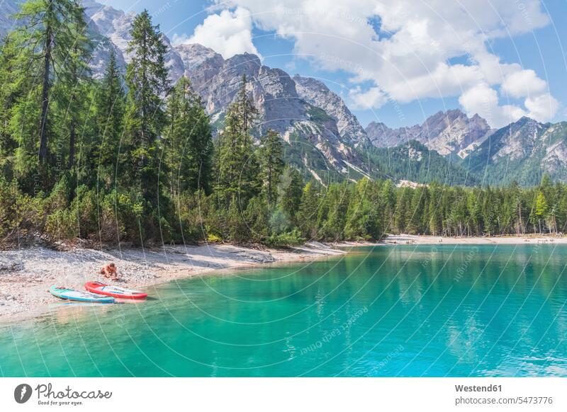 Mann mit Paddelbrettern am Ufer des Pragser Wildsees am sonnigen Tag, Dolomiten, Südtirol, Italien Farbaufnahme Farbe Farbfoto Farbphoto Außenaufnahme außen