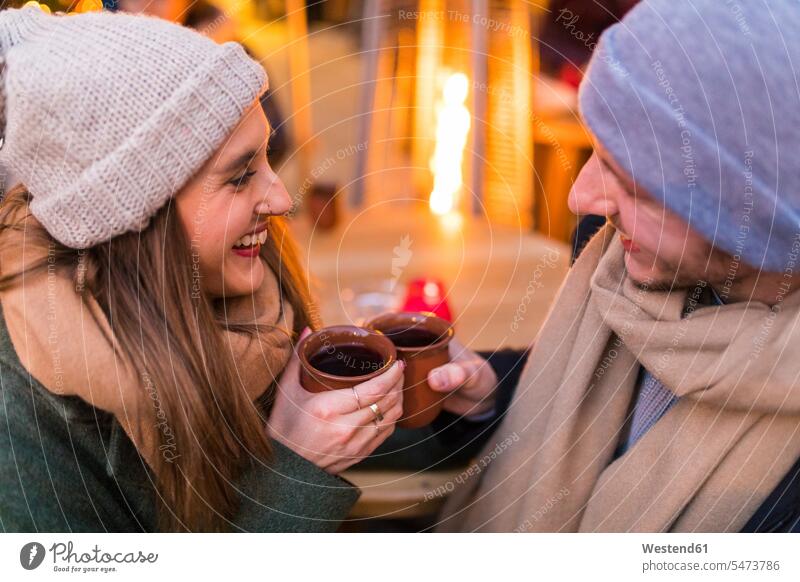 Glückliches junges Paar trinkt Glühwein auf dem Weihnachtsmarkt Christkindlmarkt glücklich glücklich sein glücklichsein Pärchen Paare Partnerschaft trinken