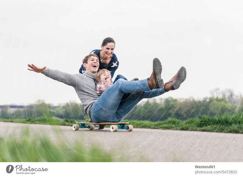 Vater und Sohn amüsieren sich, spielen mit dem Skateboard im Freien ausgeglichen Ausgeglichenheit Gleichgewicht Balance freuen Frohsinn Fröhlichkeit Heiterkeit