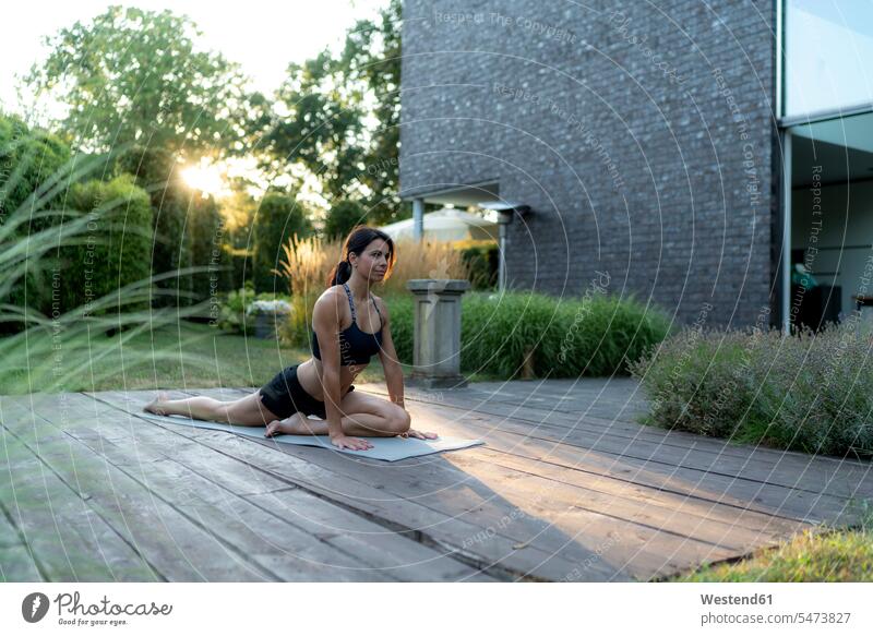 Frau übt Yoga im Garten weiblich Frauen Gärten Gaerten üben ausüben Übung trainieren Erwachsener erwachsen Mensch Menschen Leute People Personen Natur Terrasse