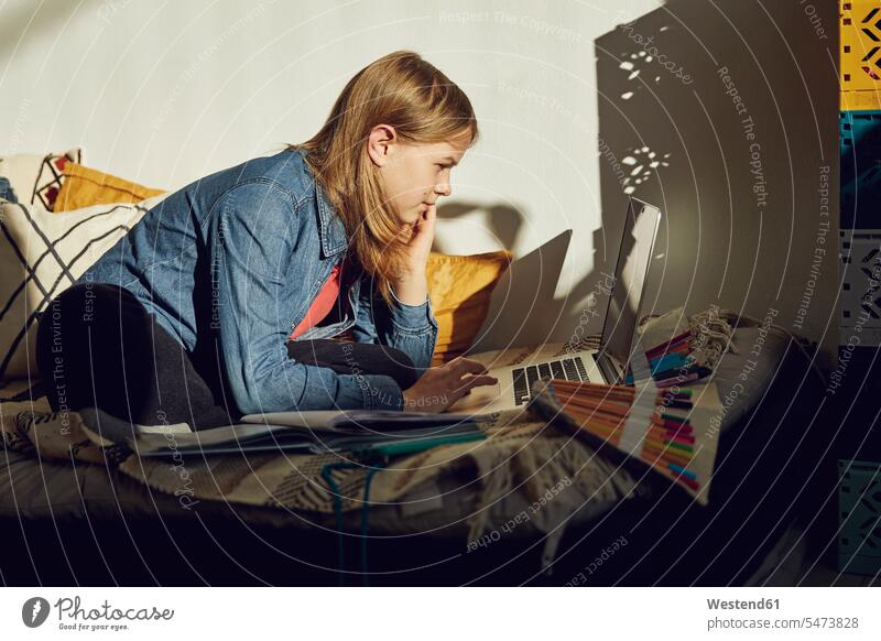 Mädchen sitzt zu Hause im Bett, macht Hausaufgaben und benutzt den Laptop E-Mail Stift Handy lernen sitzen Zuhause Internet Lifestyle Online Verbindung Allein