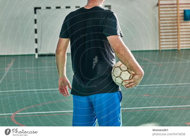 Rückansicht eines Hallenfussballers, der den Ball hält Fußball Fussball Fußballspieler Fussballspieler Fussballer Fußballer Bälle Mann Männer männlich Sport