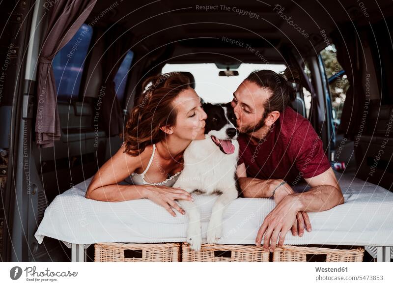 Lächelndes Paar küsst Hund, während es im Wohnwagen liegt Farbaufnahme Farbe Farbfoto Farbphoto Spanien Freizeitbeschäftigung Muße Zeit Zeit haben Hunde