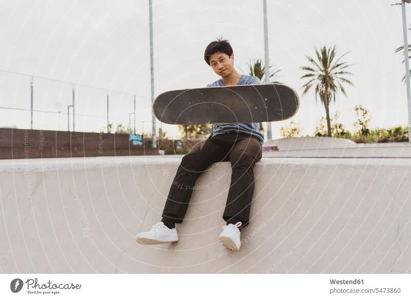 Junger Chinese sitzt an der Wand eines Skateparks in Strandnähe Chinesen chinesisches chinesischer Chinesisch jung Beach Straende Strände Beaches Skateboarder
