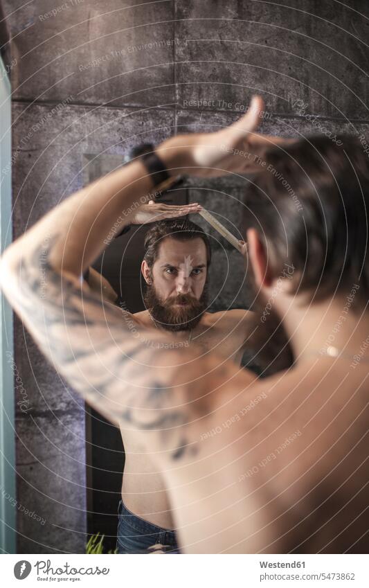 Porträt eines bärtigen Mannes, der sein Spiegelbild betrachtet, während er sein Haar kämmt kämmen Männer männlich Haare Bart Bärte Spiegelbilder Portrait