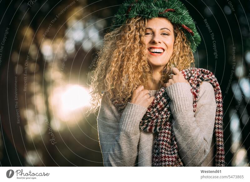 Porträt einer lachenden jungen Frau mit Weihnachtskranz auf dem Kopf Schals abends freuen Frohsinn Fröhlichkeit Heiterkeit witzig Spass spassig spaßig Spässe