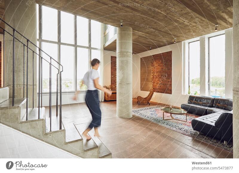 Frau, die in einer Dachgeschosswohnung die Treppe hinuntergeht Couch Couches Liege Sofas gehend Innenarchitektur Muße Individuell Stil stylisch Lifestyles