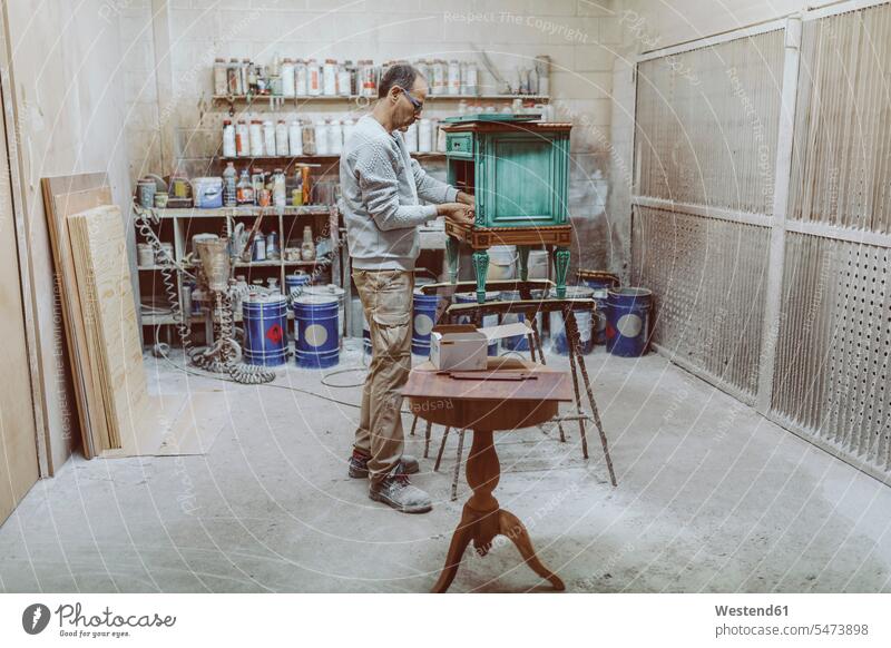Handwerker, der an antiken Möbeln arbeitet, während er in der Werkstatt steht Farbaufnahme Farbe Farbfoto Farbphoto Innenaufnahme Innenaufnahmen innen drinnen