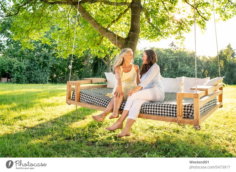 Zwei Frauen entspannen auf einem Hängebett im Garten Freundinnen Hängematte Hängematten weiblich hängen entspannt entspanntheit relaxt Gärten Gaerten Bett