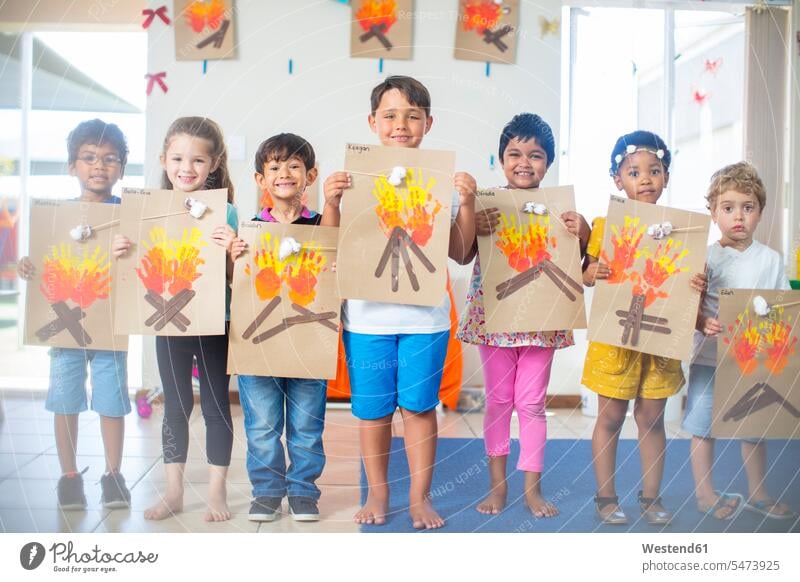 Porträt von lächelnden Kindern, die Bilder von Feuer im Kindergarten präsentieren zeigen Bildnis Portrait Porträts Portraits Kids Kindergaerten Kindergärten