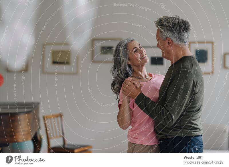 Glückliches älteres Paar tanzt zu Hause im Wohnzimmer entspannen relaxen entspanntheit relaxt freuen Frohsinn Fröhlichkeit Heiterkeit geniessen Genuss