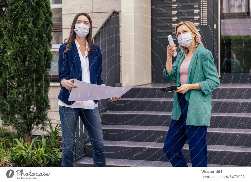 Zwei Immobilienmakler tragen Gesichtsmasken, während sie den Außenbereich des Hauses inspizieren Job Berufe Berufstätigkeit Beschäftigung Jobs geschäftlich