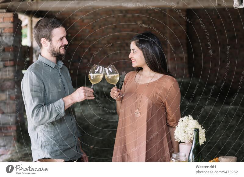 Glückliches Paar trinkt einen Cocktail und sieht sich dabei in der Scheune an Farbaufnahme Farbe Farbfoto Farbphoto Innenaufnahme Innenaufnahmen innen drinnen