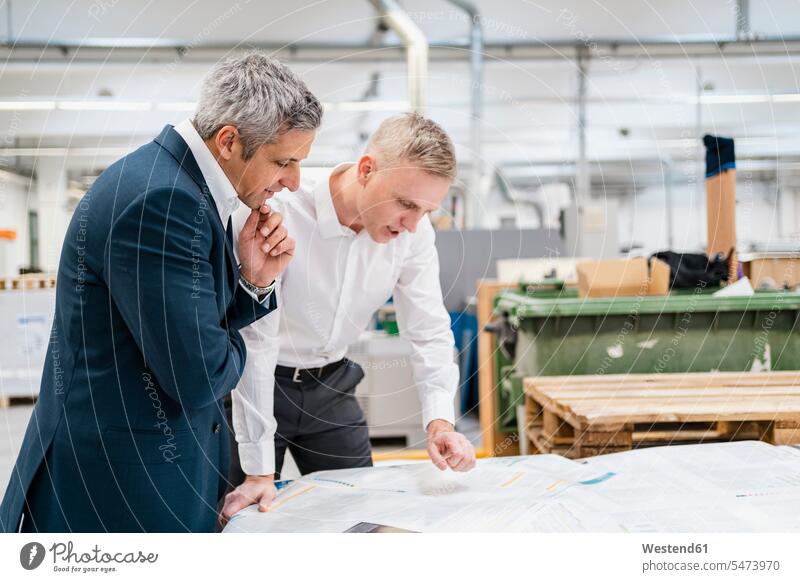 Zwei Geschäftsleute diskutieren in einer Fabrik über Papier geschäftlich Geschäftsleben Geschäftswelt Geschäftsperson Geschäftspersonen Geschäftsfreund