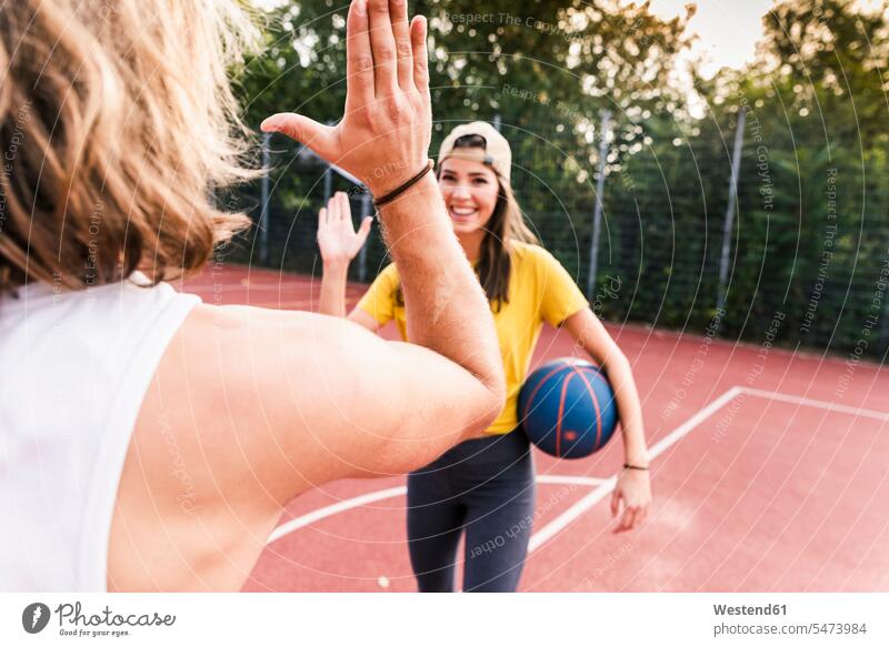Junger Mann und junge Frau High-fiving nach Basketball-Spiel Fitness fit Gesundheit gesund Sport Fairness fair abklatschen High Five aktiv trainieren Ball Bälle