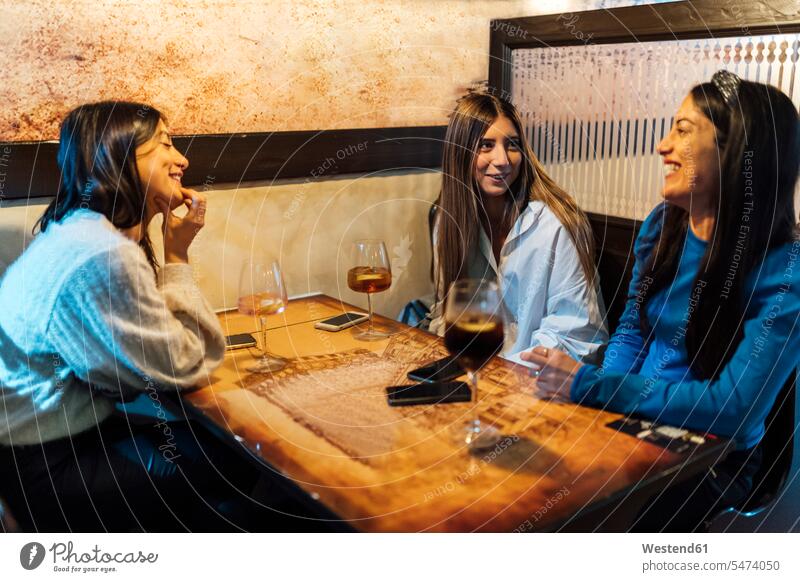 Weibliche Freunde reden, während sie Getränke in der Bar haben Farbaufnahme Farbe Farbfoto Farbphoto Innenaufnahme Innenaufnahmen innen drinnen 16-17 Jahre