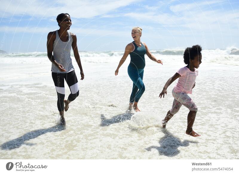 Mutter mit Tochter und Freund mit Spaß in der Brandung am Strand Freundinnen Beach Straende Strände Beaches Frau weiblich Frauen Spass Späße spassig Spässe