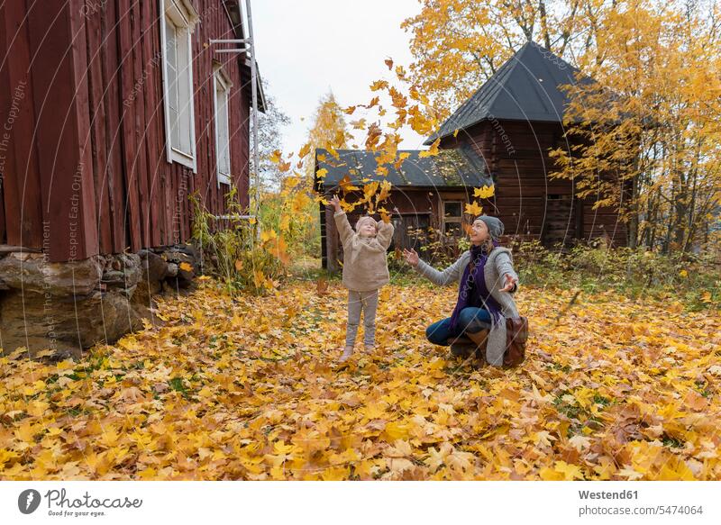 Finnland, Kuopio, Mutter und kleine Tochter, die Herbstblätter in die Luft werfen Mamas Mami Mutti Mütter Muetter Mamis Muttis Wurf Töchter Eltern Familie