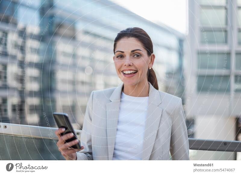 Porträt einer lächelnden Geschäftsfrau mit Mobiltelefon Geschäftsfrauen Businesswomen Businessfrauen Businesswoman Portrait Porträts Portraits Smartphone iPhone