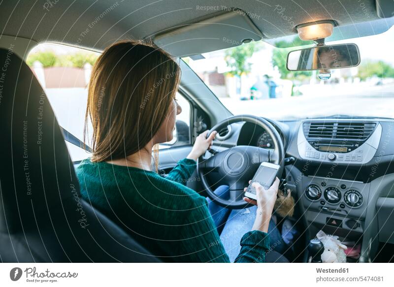 Frau tippt im Auto auf dem Mobiltelefon Gefahr gefaehrlich Gefahren gefährlich weiblich Frauen fahrend fahrender fahrendes autofahren Wagen PKWs Automobil Autos
