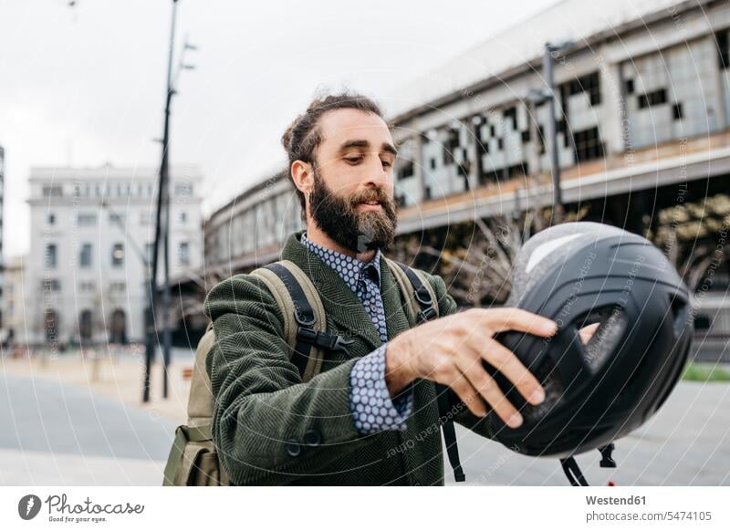Porträt eines Mannes beim Aufsetzen eines Fahrradhelms in der Stadt Portrait Porträts Portraits Radhelm Fahrradhelme aufsetzen Männer männlich staedtisch