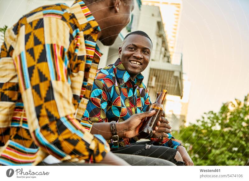 Freunde sitzen auf der Dachterrasse in der Stadt und trinken Bier, Maputo, Mosambik Kameradschaft Flaschen Bierflaschen Hemden sitzend sitzt reden entspannen