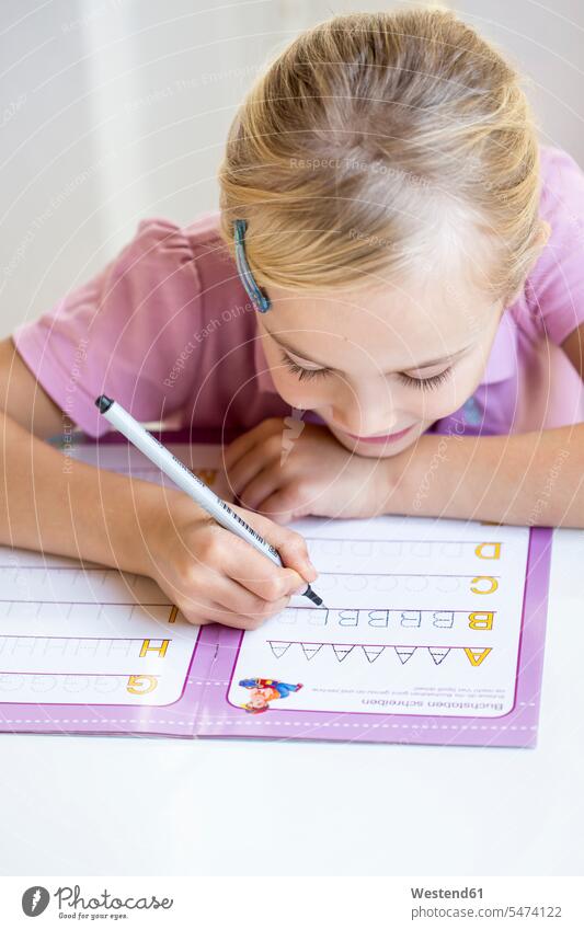 Kleines Mädchen schreibt Alphabet schreiben Kind Mensch Freizeitkleidung blond Hausaufgaben Vorderansicht Heft Zufriedenheit eine Person üben Europäer Schulheft