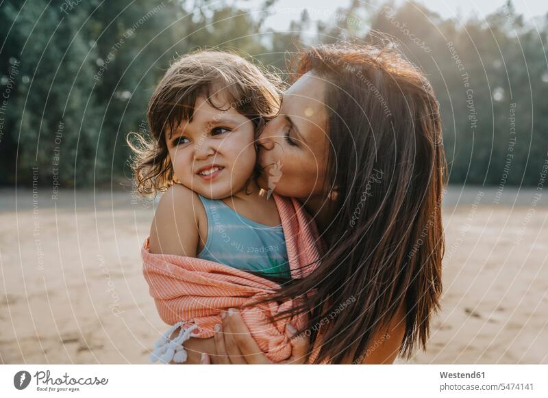 Mutter küsst Tochter am Strand an einem sonnigen Tag Farbaufnahme Farbe Farbfoto Farbphoto Außenaufnahme außen draußen im Freien Tageslichtaufnahme