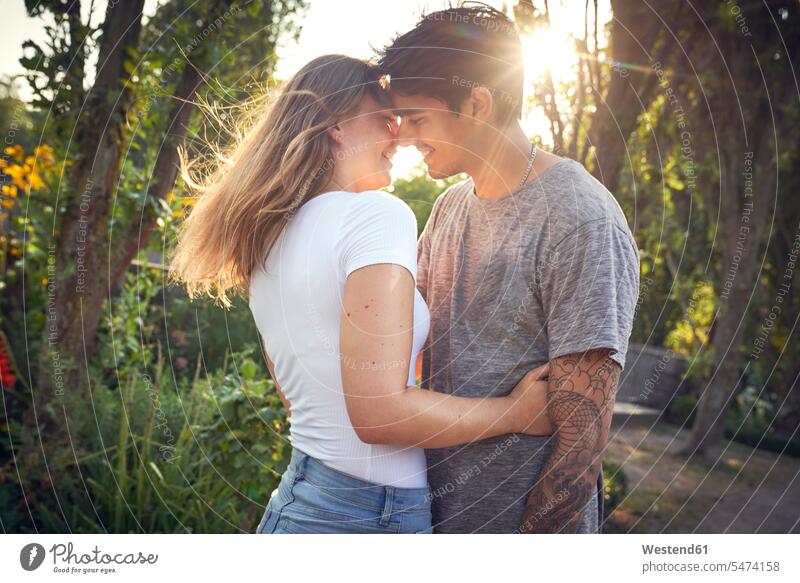 Glückliches junges Paar umarmt und küsst in einem Park im Sommer berühren Berührung anfassen Parkanlagen Parks frisch verliebt sich verlieben Junges Paar