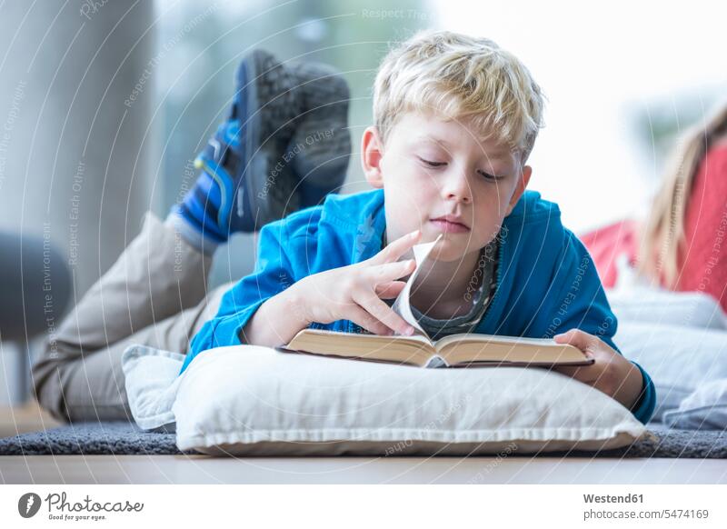 Auf dem Boden liegender Schüler liest Buch im Pausenraum der Schule Böden Boeden lesen Lektüre Schulen Schuljunge liegt Bücher lernen Intelligenz klug Klugheit