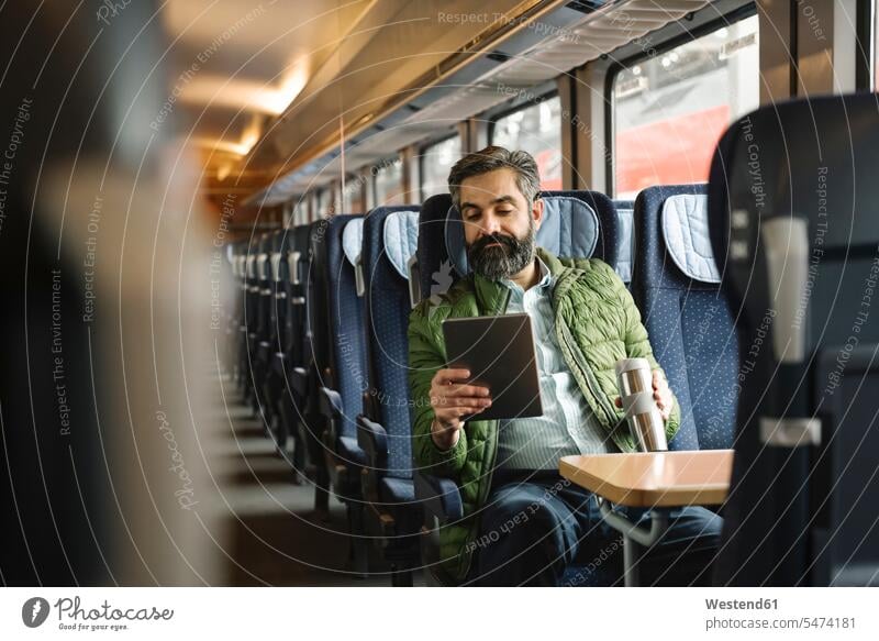 Mann sitzt mit Tablette im Zug Job Berufe Berufstätigkeit Beschäftigung Jobs geschäftlich Geschäftsleben Geschäftswelt Geschäftsperson Geschäftspersonen