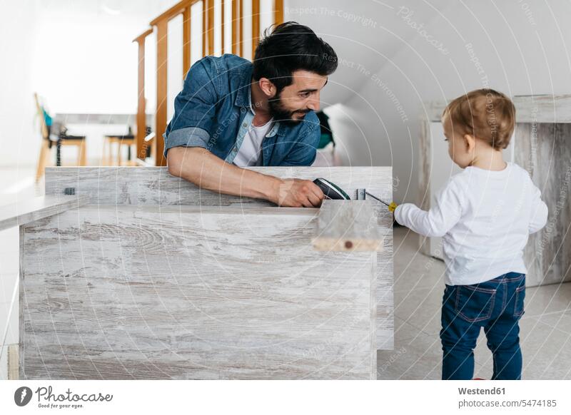 Vater und Tochter bauen zu Hause einen Holztisch zusammen Gemeinsam Zusammen Miteinander Heimwerken Do-it-Yourself DIY Möbel Mobiliar Einrichtungsgegenstand