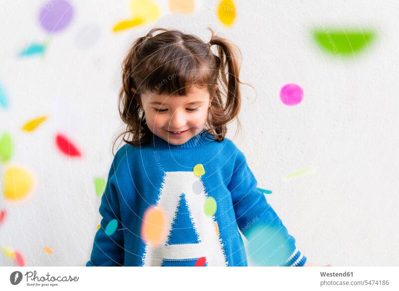 Glückliches kleines Mädchen mit dem Konfetti während einer Party vor einer weißen Wand Leute Menschen People Person Personen Europäisch Kaukasier kaukasisch